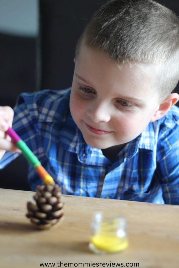 A boy painting pinecones.